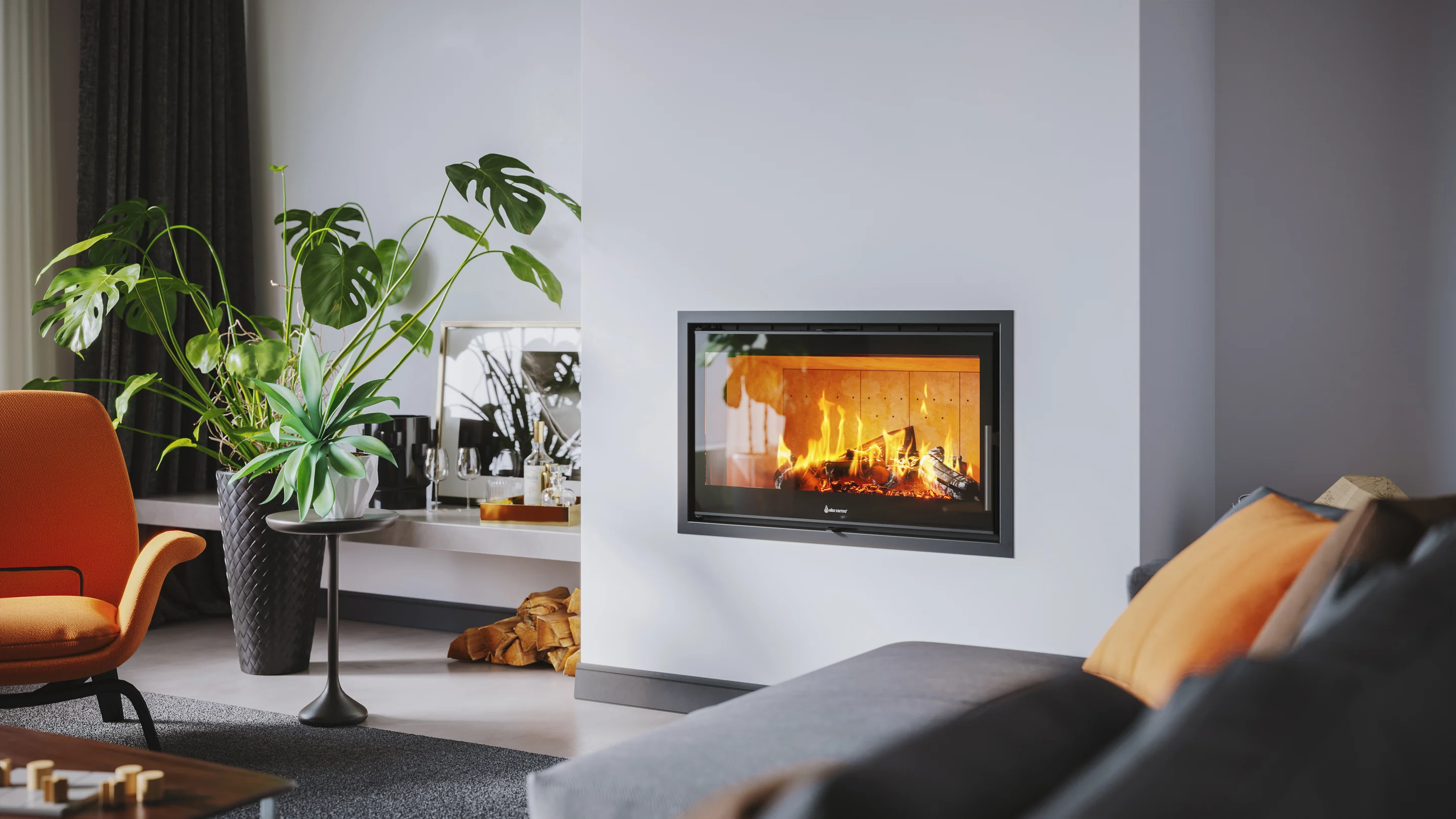 Estufa insertable Vantage I3 encendida en una pared blanca de un living, con plantas y un sillón naranja
